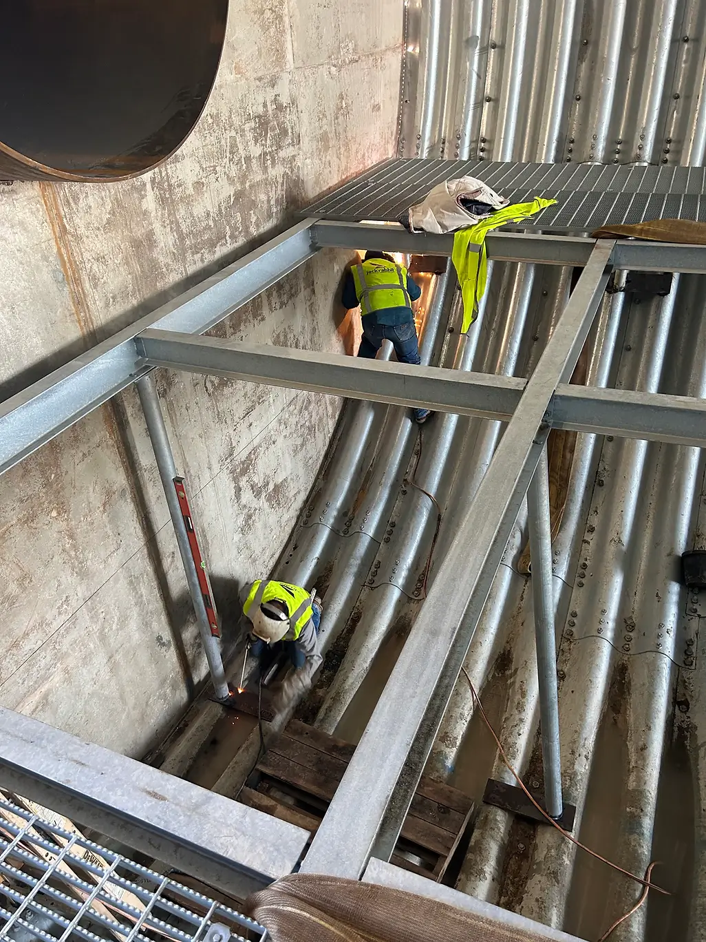 metalworkers in high visibility vests assembling i-beams at an outdoor project